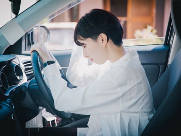 車での交通事故で頭を押さえている女性